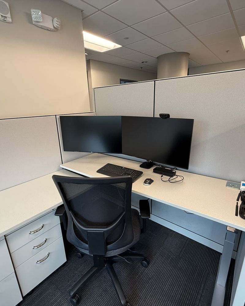 A finished office workstation with dual monitors, a ceiling speaker and a wireless access point overhead